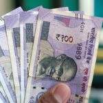 Close-up view of holding Indian 100 rupee banknotes, showcasing currency details and design.